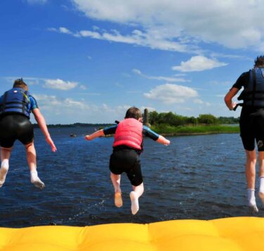 Children jumping off an inflatable into the river at Baysports