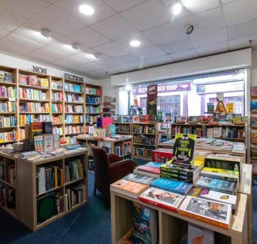 Inside of Athlone Bookshop with wall to wall bookshelves, full of books with four tables in the middle with more books