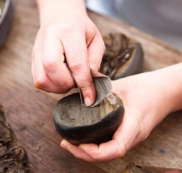 Hands crafting a item made by bog oak on a table