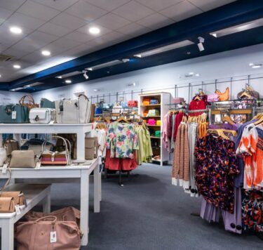 Interior of Burgess of Athlone. A wide array of bright, colourful clothes on racks and handbags displayed on shelves