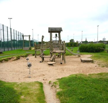 Children's playground with wooden climbing frames and sandpit.