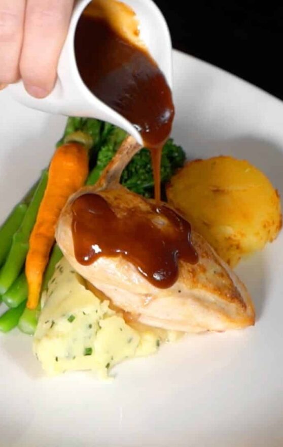 Delicious chicken cutlet with gravy being poured over it accompanied by crisp vegetables at Shamrock Lodge Hotel Athlone