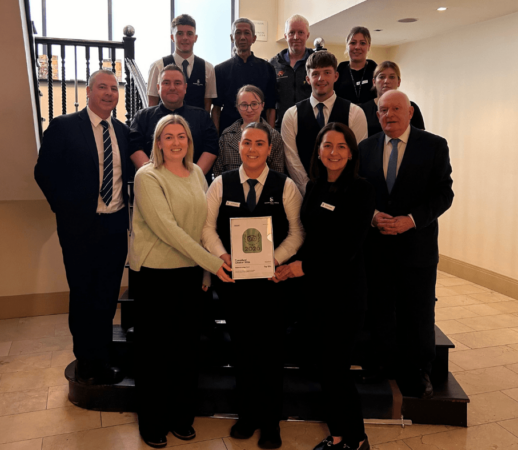 Friendly hotel staff on elegant staircase showcasing warm hospitality and award.